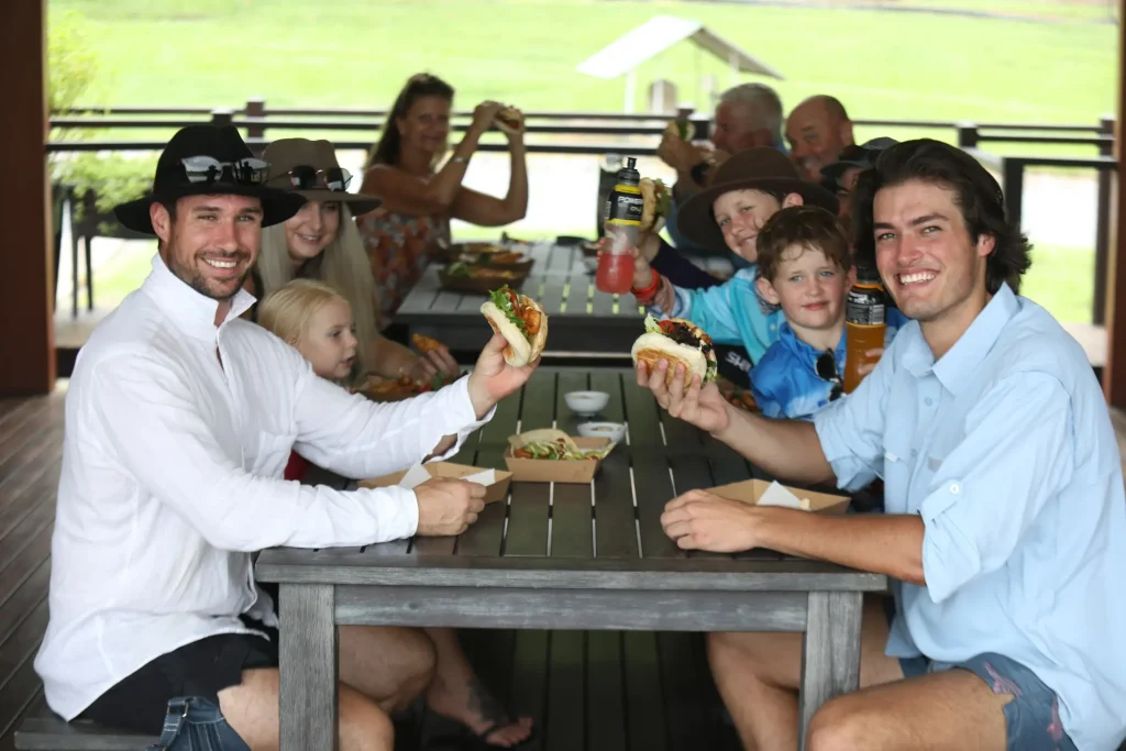 Happy group of people eating fish sandwich at table